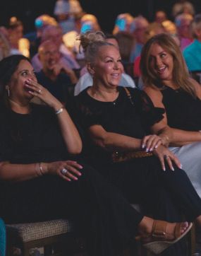 Women laughing in the front row of a theate